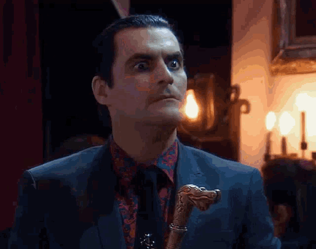 a man in a suit is holding a cane with a dragon handle