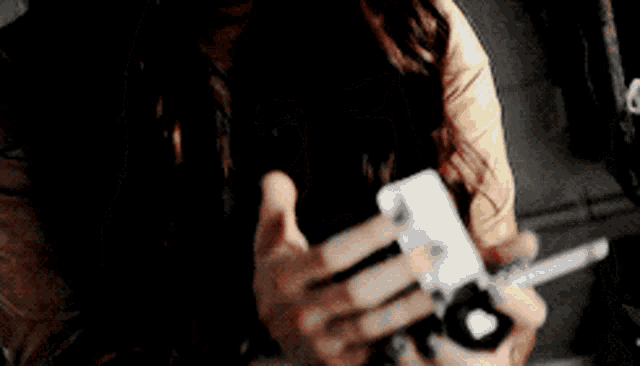 a woman is holding a remote control in her hand and looking at the camera .