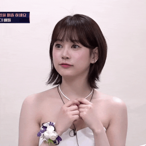 a woman in a white dress has a wristband with flowers on it in front of a sign that says ' korean '