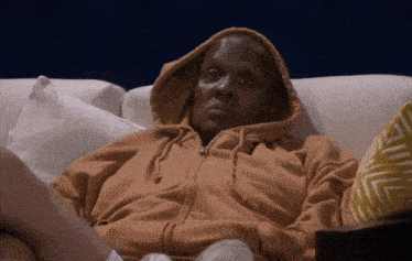 a man in a hoodie is laying on a couch