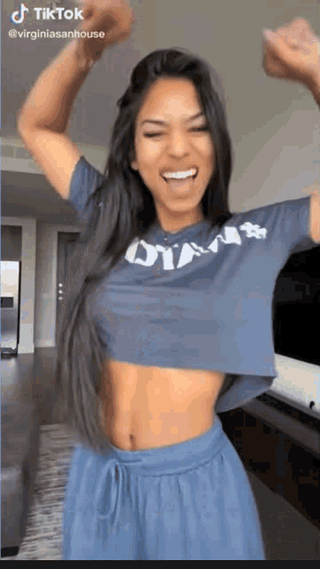 a woman wearing a blue crop top and blue shorts is dancing in a living room .