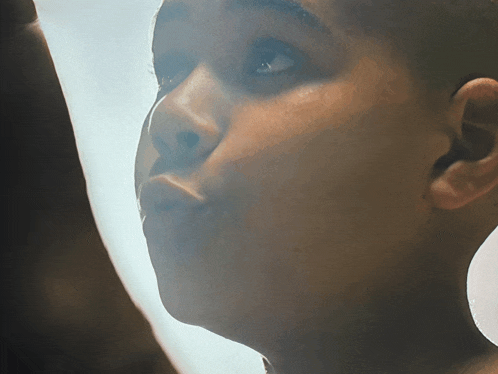 a close up of a person 's face with a white curtain behind them