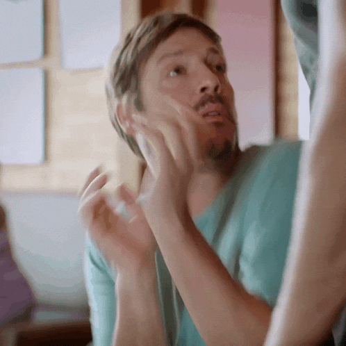 a man with a beard is looking at his face in a mirror and making a funny face .