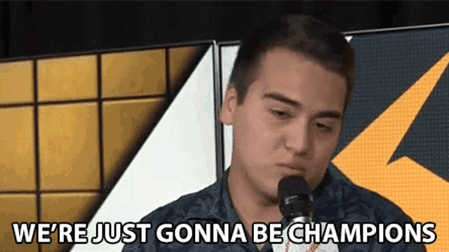 a man is speaking into a microphone and saying we 're just gonna be champions .