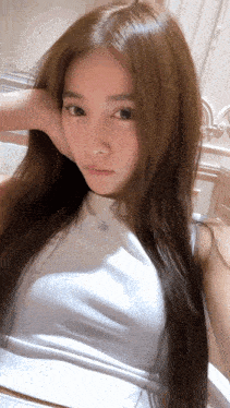 a woman with long hair is wearing a white top and necklace