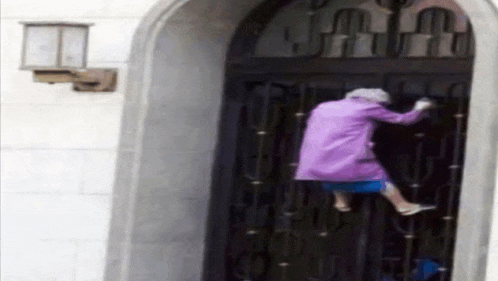 a woman in a purple coat is knocking on a black door