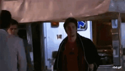 a man in a red shirt is walking in front of a sign that says ' rbd.gif '