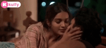 a woman is kissing a man on the cheek while laying on a bed .