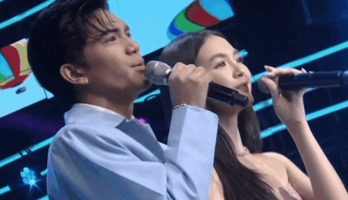 a man and a woman are singing into microphones on a stage