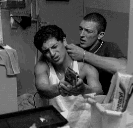 a black and white photo of two men in a bathroom with a tube of trench toothpaste on the counter