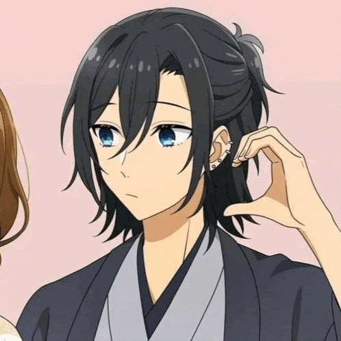 a man with long black hair and blue eyes is getting his ear pierced by a woman