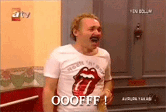 a man wearing a rolling stones shirt is laughing