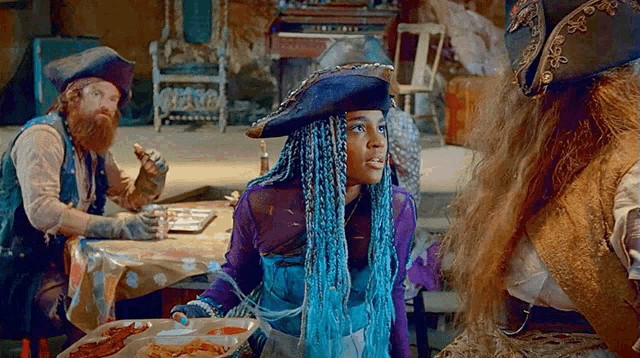 a girl with blue dreadlocks is standing in front of a table with plates of food .