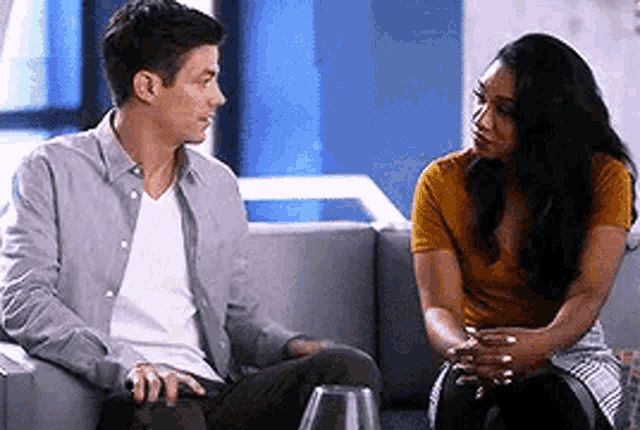 a man and a woman are sitting on a couch talking .