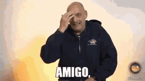 a bald man in a blue jacket says amigo on his face