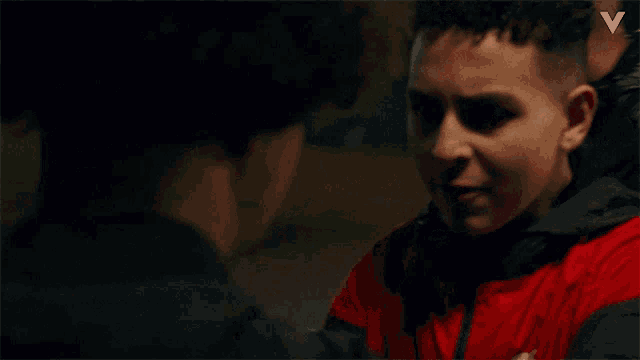 a man in a red jacket is talking to another man in a black jacket