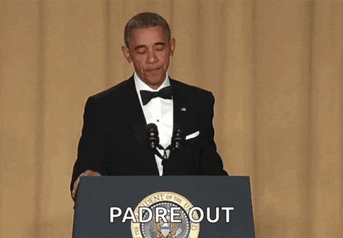 a man in a suit and tie is standing at a podium holding a microphone and covering his mouth .
