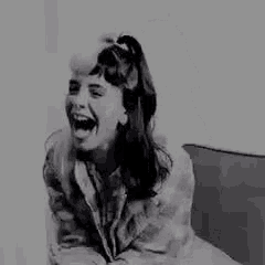 a black and white photo of a woman laughing .