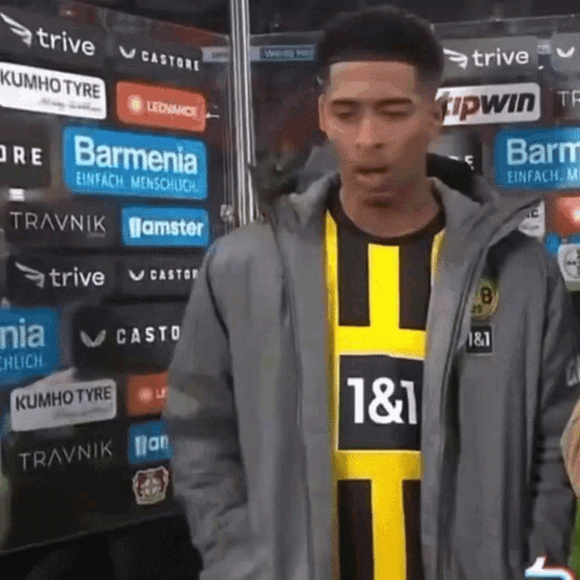 a man wearing a jacket and a yellow and black shirt with the number 1 & 1 on it