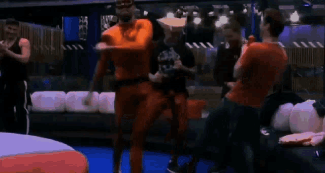 a group of men are standing in a room and one of them is wearing a red shirt .