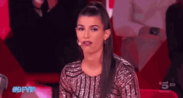a woman in a sequined top is sitting on a red couch with the hashtag #gfvip on the bottom