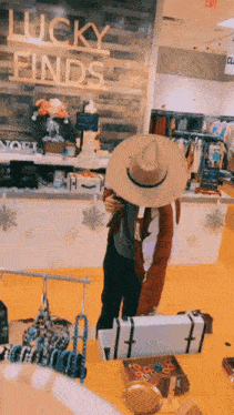 a woman wearing a cowboy hat is standing in front of a lucky finds sign