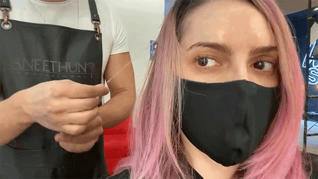 a woman with pink hair is wearing a black apron that says neethun on it
