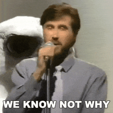a man singing into a microphone with the words we know not why below him .