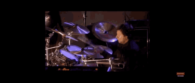 a man is playing drums in a dark room in a video .