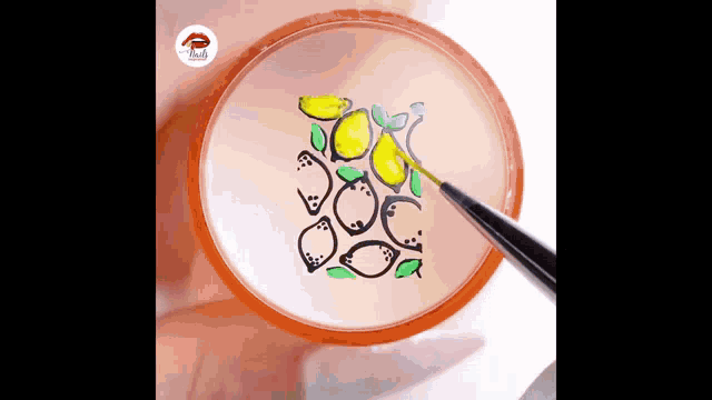a person is painting lemons with a brush on a plate