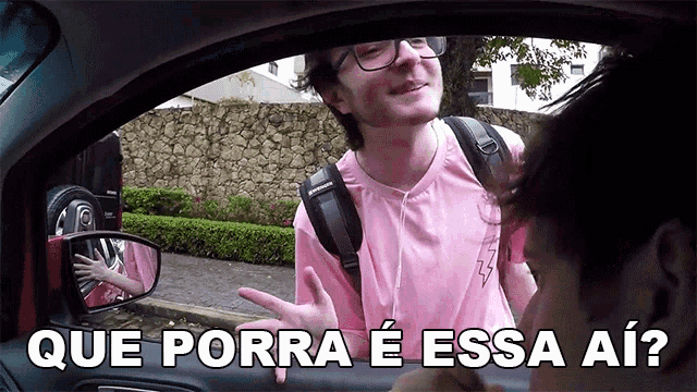 a man in a pink shirt is talking to another man in a car with que porra e essa ai
