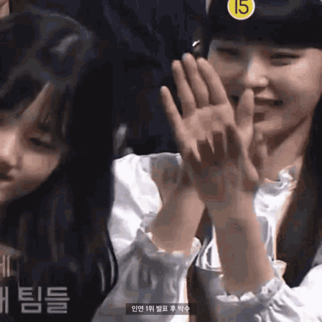 two young girls are giving each other a high five while wearing a hat with the number 15 on it .