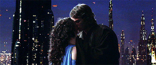 a man and a woman are kissing in front of a city skyline at night