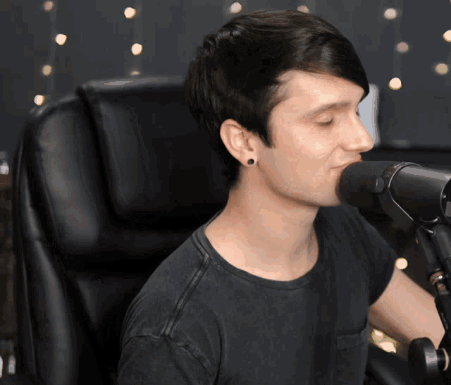 a man is singing into a microphone while wearing a black shirt