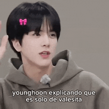 a younghoon is wearing a bow in his hair and a hoodie .