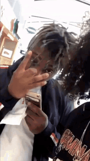 a man with dreadlocks is holding a cell phone in his hand