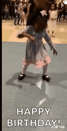 a little girl in a pink dress is dancing in a room with other children .