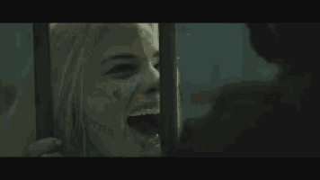 a woman is laughing behind bars in a dark room while a man holds her hand .