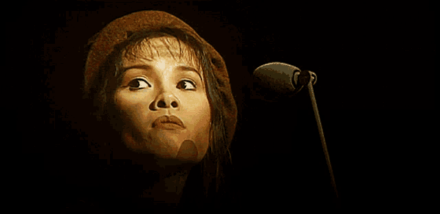 a close up of a woman 's face with a microphone behind her
