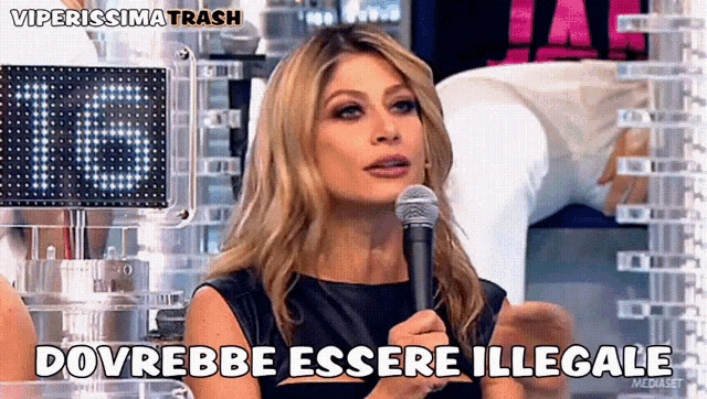 a woman speaking into a microphone with the words dovrebbe essere illegale written below her