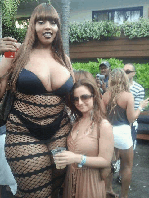 a woman in a fishnet outfit stands next to a woman in sunglasses