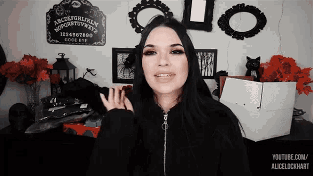 a woman standing in front of a ouija board that says good bye