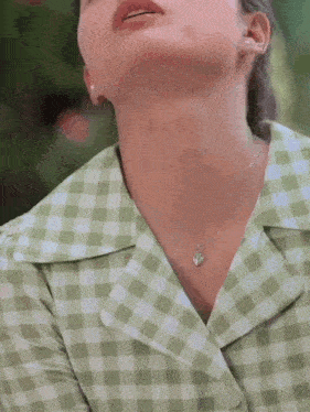 a woman wearing a green and white checkered shirt and a heart shaped necklace