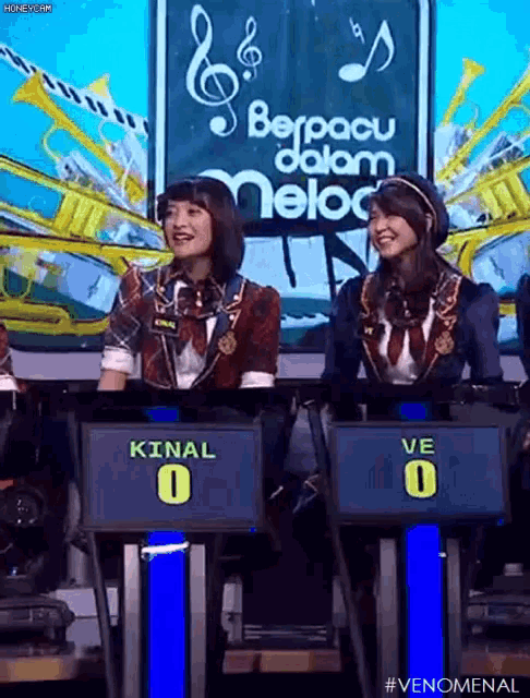 two women are sitting in front of a screen with the number 0 on it
