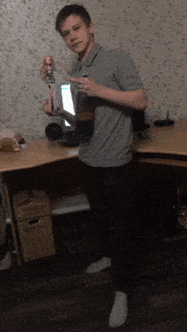 a man in a grey shirt is holding a doll and pointing