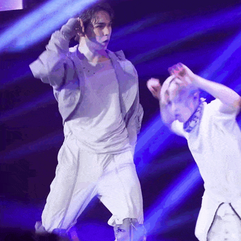 a man in a white shirt is dancing on a stage with a blue light behind him