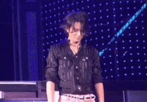 a man in a black shirt and pink pants is standing on a stage