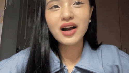a close up of a woman 's face with her mouth open and a blue jacket on .