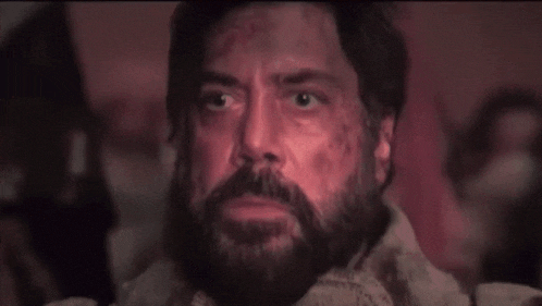 a man with a beard is sitting in a dark room and looking up at the sky .