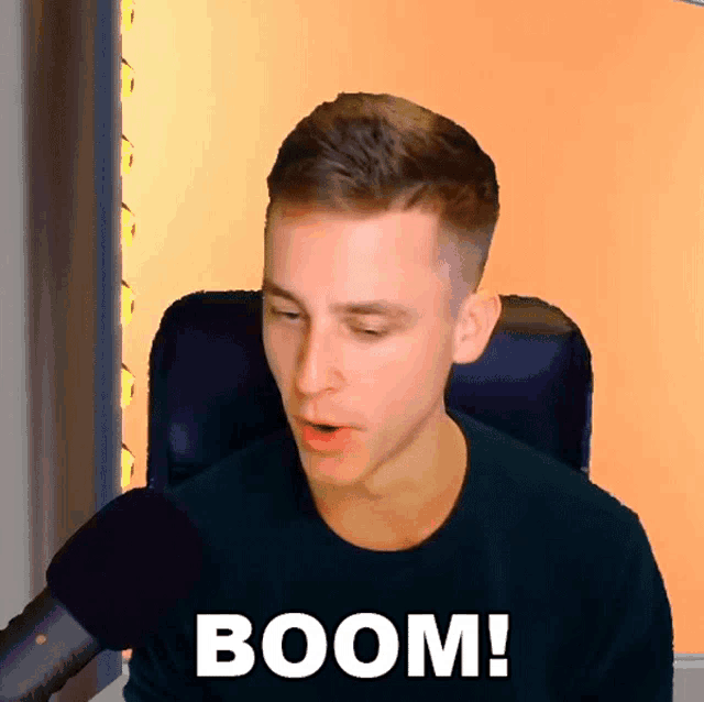 a man sitting in front of a microphone with the word boom written on his shirt